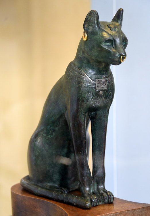 A bronze statue the cat wears golden earrings and nose-ring and a silver wedjat (Eye of Horus). Around 600 BC from Saqqara, Egypt in The British Museum, London